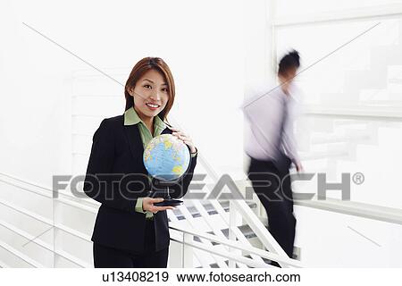 Portrait of a businesswoman holding a globe and smiling View Large Photo Image Stock Photo - Portrait of a businesswoman holding a globe and smiling. Fotosearch