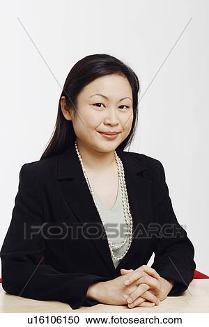 Stock Image - Portrait of a businesswoman sitting in an office and smiling. Fotosearch