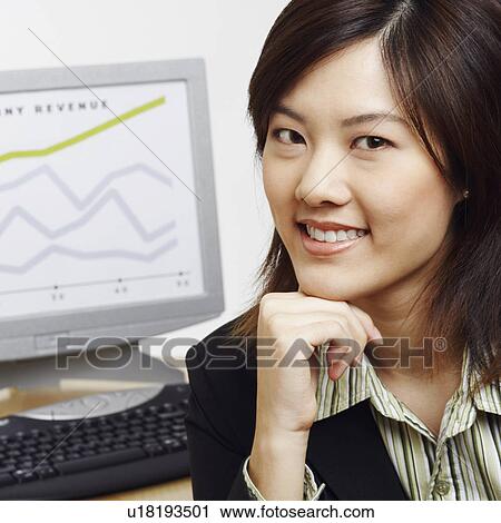 Stock Image - Portrait of a businesswoman smiling with a progress report in the background. Fotosearch