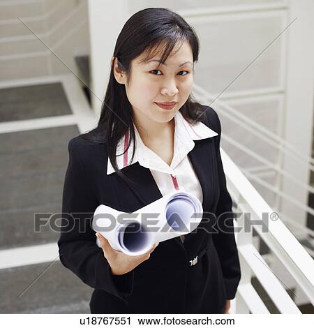Portrait of a female architect holding rolled up blueprints and smiling View Large Photo Image Stock Image - Portrait of a female architect holding rolled up blueprints and smiling. Fotosearch