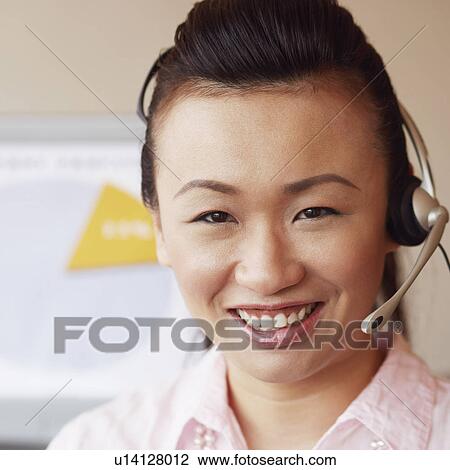 Stock Image - Portrait of a female customer service representative talking on a headset and smiling. Fotosearch