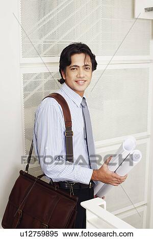 Portrait of a male architect holding rolled up blueprints and smiling View Large Photo Image Stock Photography - Portrait of a male architect holding rolled up blueprints and smiling. Fotosearch