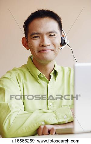 Portrait of a male customer service representative using a laptop and smiling View Large Photo Image Stock Photo - Portrait of a male customer service representative using a laptop and smiling. Fotosearch