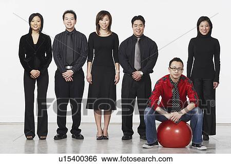 Portrait of a young man sitting on a ball with a group of business executives standing beside him View Large Photo Image Stock Photograph - Portrait of a young man sitting on a ball with a group of business executives standing beside him. Fotosearch