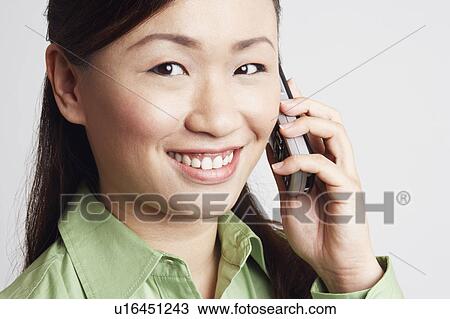 Portrait of a young woman talking on a mobile phone and smiling View Large Photo Image Stock Image - Portrait of a young woman talking on a mobile phone and smiling. Fotosearch