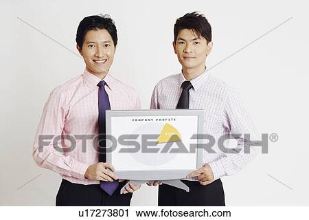 Portrait of two businessmen holding a progress report and smiling View Large Photo Image Stock Image - Portrait of two businessmen holding a progress report and smiling. Fotosearch