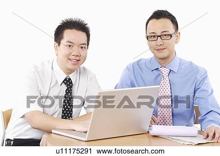 Stock Image - Portrait of two businessmen sitting in front of a laptop. Fotosearch