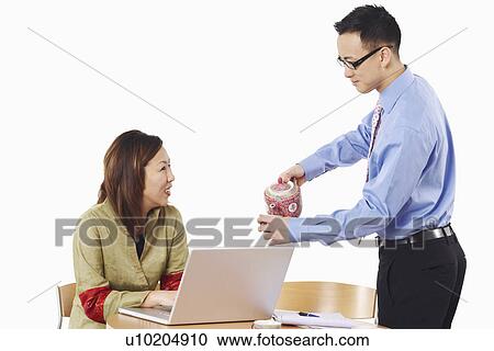 Side profile of a businessman pouring tea into a teacup in front of a businesswoman View Large Photo Image Stock Image - Side profile of a businessman pouring tea into a teacup in front of a businesswoman. Fotosearch