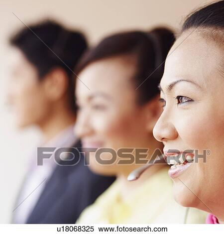 Side profile of a female customer service representative smiling with two colleagues View Large Photo Image Stock Photography - Side profile of a female customer service representative smiling with two colleagues. Fotosearch