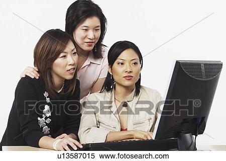 Close-up of three businesswomen looking at a computer View Large Photo Image Stock Photography - Close-up of three businesswomen looking at a computer. Fotosearch