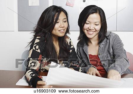 Stock Photo - Close-up of two businesswomen reading documents. Fotosearch