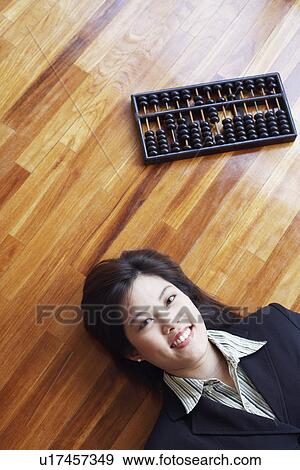 Stock Photo - High angle view of a businesswoman lying on the hardwood floor and smiling. Fotosearch