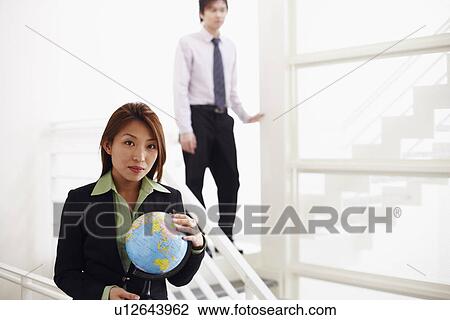 Stock Image - Portrait of a businesswoman holding a globe. Fotosearch