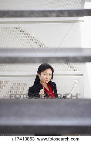 Stock Image - Portrait of a businesswoman holding a newspaper and posing. Fotosearch