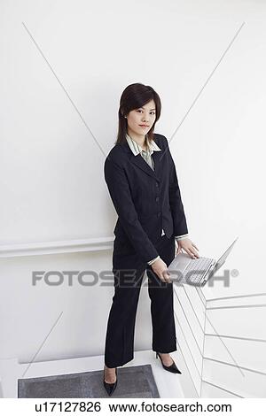 Portrait of a businesswoman holding a laptop View Large Photo Image Stock Photograph - Portrait of a businesswoman holding a laptop. Fotosearch