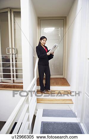 Stock Photography - Portrait of a businesswoman holding a newspaper and smiling. Fotosearch