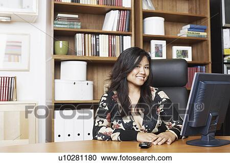 Portrait of a businesswoman sitting in front of a computer smiling View Large Photo Image Stock Image - Portrait of a businesswoman sitting in front of a computer smiling. Fotosearch