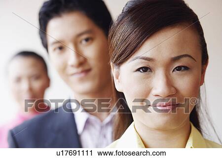 Stock Image - Portrait of a businesswoman smiling with her colleagues. Fotosearch