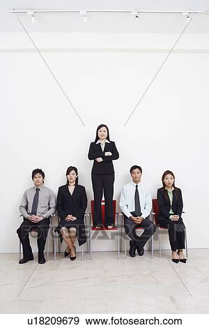 Portrait of a businesswoman standing on an armchair with four business executives sitting beside her View Large Photo Image Stock Photo - Portrait of a businesswoman standing on an armchair with four business executives sitting beside her. Fotosearch
