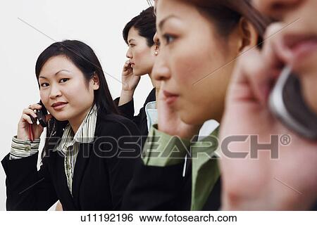 Portrait of a businesswoman talking on a mobile phone with his colleagues View Large Photo Image Stock Photograph - Portrait of a businesswoman talking on a mobile phone with his colleagues. Fotosearch
