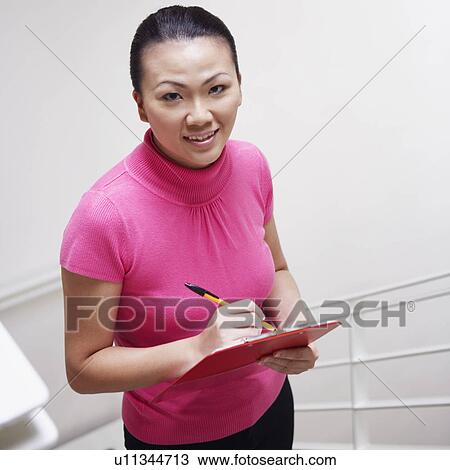 Stock Image - Portrait of a businesswoman walking up a staircase and smiling. Fotosearch