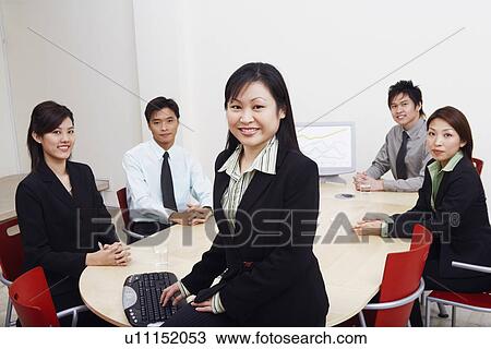 Stock Image - Portrait of business executives sitting in a board room. Fotosearch