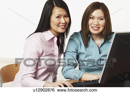 Stock Photograph - Portrait of two businesswomen using a computer. Fotosearch