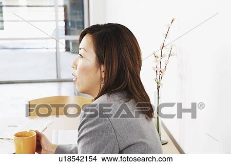 Picture - Side profile of a businesswoman holding a cup. Fotosearch