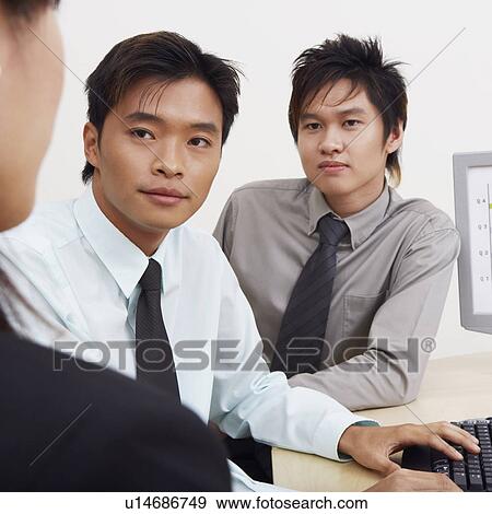 Two businessmen and a businesswoman sitting together in an office View Large Photo Image Stock Photo - Two businessmen and a businesswoman sitting together in an office. Fotosearch