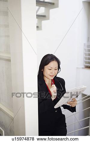 Stock Photo - Businesswoman holding a newspaper and smiling. Fotosearch