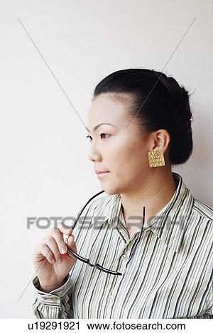 Close-up of a businesswoman holding eyeglasses and looking away View Large Photo Image Stock Image - Close-up of a businesswoman holding eyeglasses and looking away. Fotosearch
