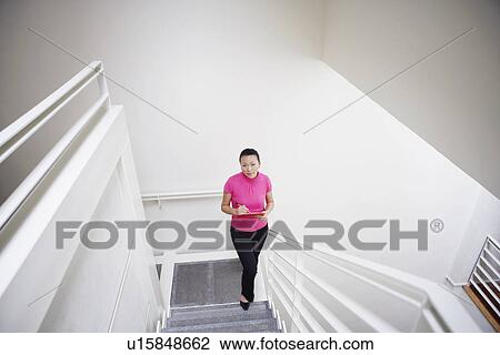 Stock Image - High angle view of a businesswoman walking up a staircase. Fotosearch