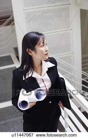 High angle view of a female architect standing on the staircase and holding rolled up blueprints View Large Photo Image Stock Photo - High angle view of a female architect standing on the staircase and holding rolled up blueprints. Fotosearch