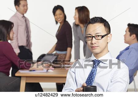 Portrait of a businessman sitting on a chair holding a coffee cup View Large Photo Image Stock Photo - Portrait of a businessman sitting on a chair holding a coffee cup. Fotosearch