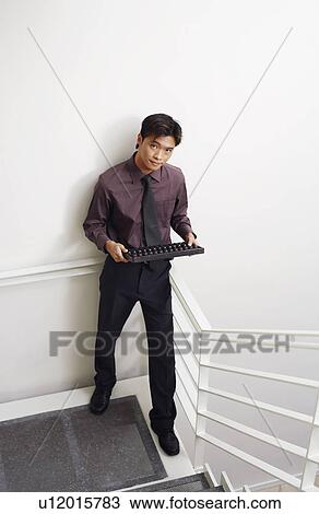 Portrait of a businessman standing on a staircase and holding an abacus View Large Photo Image Stock Image - Portrait of a businessman standing on a staircase and holding an abacus. Fotosearch