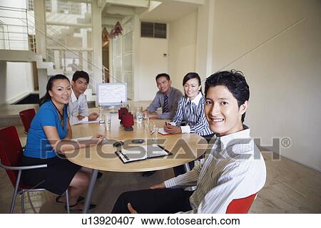 Portrait of two businesswomen with three businessmen sitting at a conference table View Large Photo Image Stock Photo - Portrait of two businesswomen with three businessmen sitting at a conference table. Fotosearch