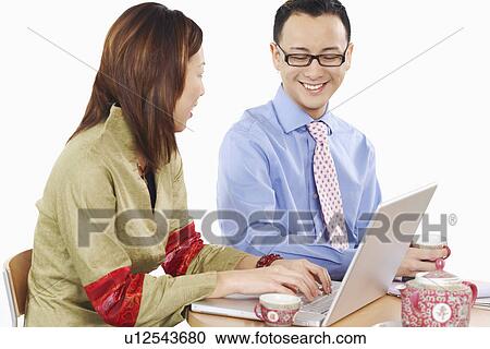 Stock Image - Side profile of a businesswoman and a businessman using a laptop. Fotosearch