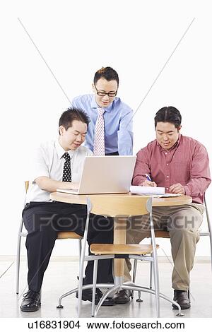 Three businessmen discussing in front of a laptop View Large Photo Image Picture - Three businessmen discussing in front of a laptop. Fotosearch
