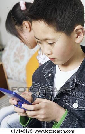 Close-up of a boy playing a video game View Large Photo Image Stock Image - Close-up of a boy playing a video game. Fotosearch