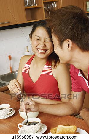 Close-up of a young couple having breakfast and smiling at a kitchen counter View Large Photo Image Stock Photo - Close-up of a young couple having breakfast and smiling at a kitchen counter. Fotosearch