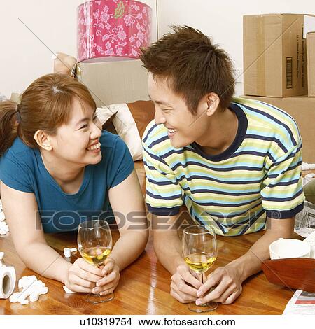 Close-up of a young couple lying on the floor and holding glasses of wine View Large Photo Image Picture - Close-up of a young couple lying on the floor and holding glasses of wine. Fotosearch