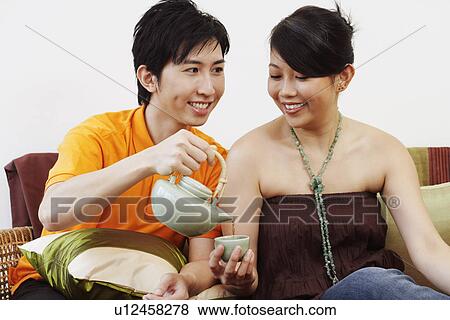 Stock Photo - Close-up of a young man pouring coffee in a cup held by a young woman. Fotosearch