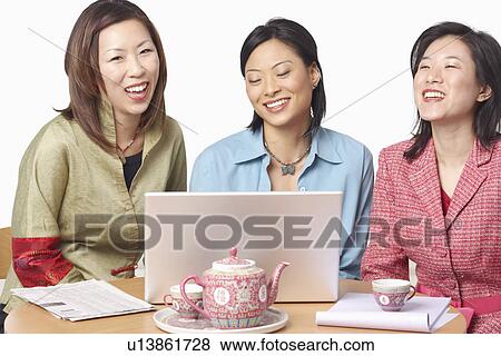 Stock Photo - Close-up of three businesswomen in front of a laptop. Fotosearch