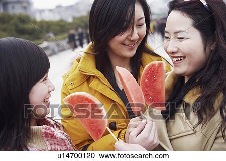 Stock Image - Close-up of three young women holding watermelons. Fotosearch