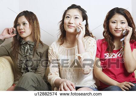 Picture - Close-up of three young women talking on mobile phones. Fotosearch