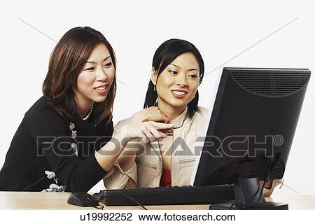 Close-up of two businesswomen looking at a computer View Large Photo Image Stock Image - Close-up of two businesswomen looking at a computer. Fotosearch