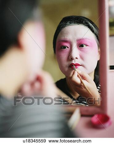 Rear view of a young woman applying lip liner View Large Photo Image Stock Photo - Rear view of a young woman applying lip liner. Fotosearch