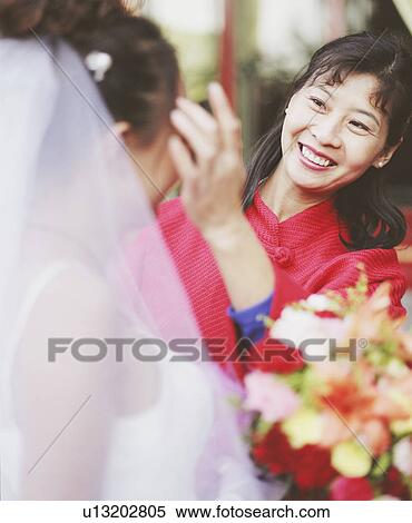 Young woman adjusting the hair of another woman in the wedding dress View Large Photo Image Stock Photography - Young woman adjusting the hair of another woman in the wedding dress. Fotosearch