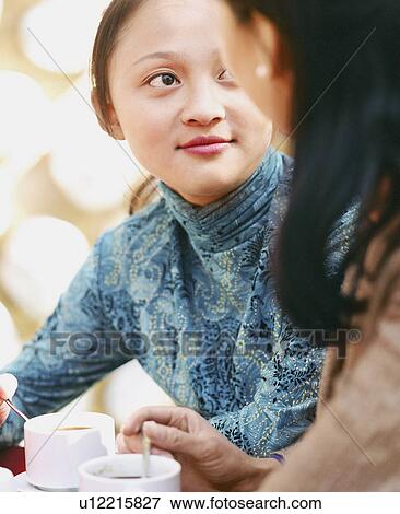 Stock Photo - Young woman sitting in a restaurant with another woman. Fotosearch