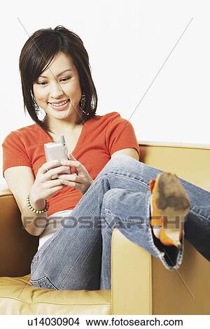 Picture - Close-up of a young woman operating a mobile phone. Fotosearch